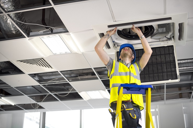 electrician fitting air conditioning to office interior Location de chauffage pour un installateur CVC